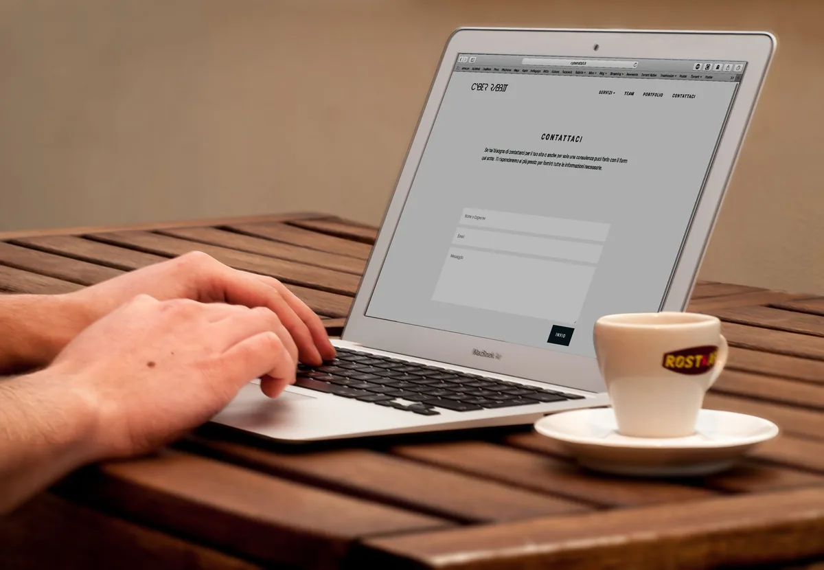 Page de contact d'un site vitrine affichée sur un ordinateur portable, sur une table en bois